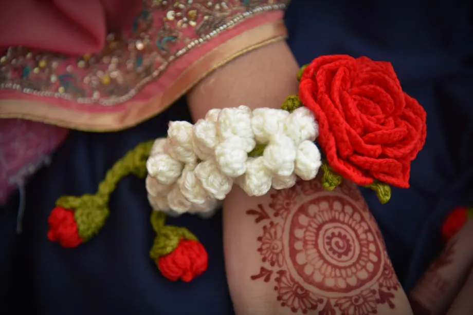 Close-up of a red crochet rose with white motia and dangling rosebuds